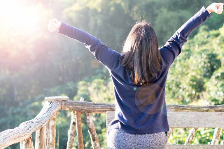 une femme debout sur son balcon se réveille en bonne santé